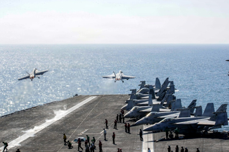 Photo diffusée par l'US Navy et publiée par le service des affaires publiques du Commandement central américain montrant deux F/A-18 Super Hornets décollant du pont d'envol du porte-avions USS Abraham Lincoln en soutien à l'opération Epic Fury, le 3 mars 2026 ( US NAVY / - )