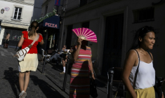 Une passante se protège du soleil avec un éventail à Montmartre, à Paris, le 12 août 2025, en pleine vague de chaleur ( AFP / Martin LELIEVRE )