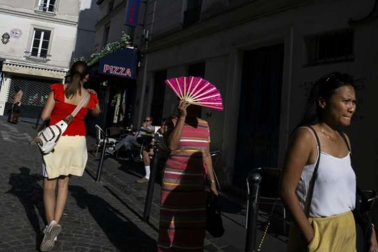 Une passante se protège du soleil avec un éventail à Montmartre, à Paris, le 12 août 2025, en pleine vague de chaleur ( AFP / Martin LELIEVRE )