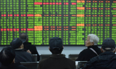Les investisseurs se tiennent devant un tableau affichant des informations dans une maison de courtage lors du premier jour de négociation en Chine depuis le Nouvel An lunaire 2020 à Hangzhou, dans la province chinoise du Zhejiang
