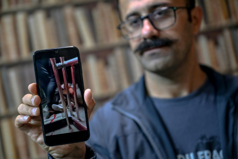 Farhad Sheikhi, un Kurde iranien qui a rejoint les manifestations antigouvernementales en 2022, montre des images des manifestations en Iran lors d'une interview à Souleimaniyeh, le 12 mars 2026 en Irak ( AFP / Ozan KOSE )