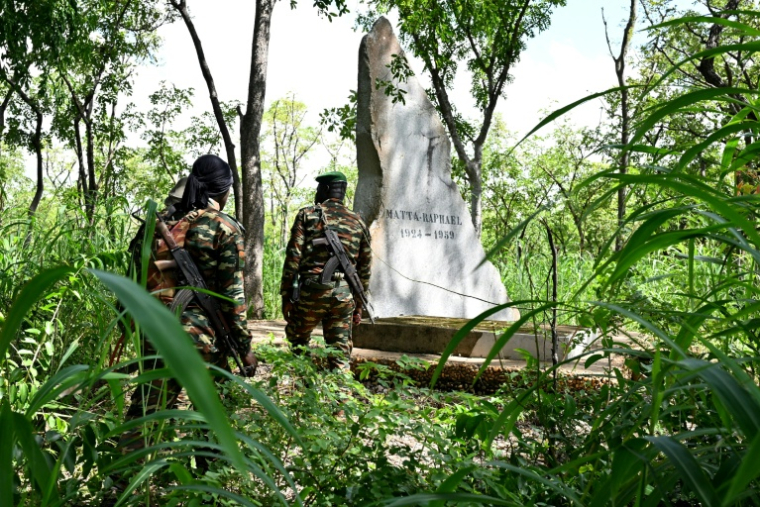 Des gardes forestiers devant la tombe de Raphaël Matta, tué par des braconniers en 1959, dans le parc national de la Comoé, le 10 octobre 2025 au nord-est de la Côte d'Ivoire ( AFP / Issouf SANOGO )