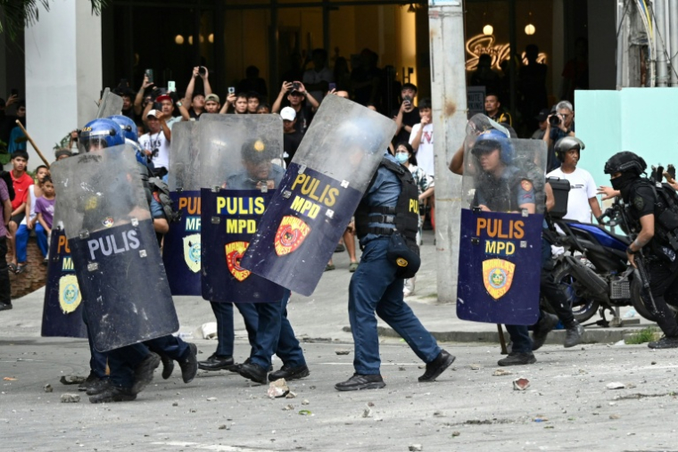 Des policiers se protègent de jets de pierre lors d'une manifestation à Manille le 21 septembre 2025 ( AFP / Ted ALJIBE )