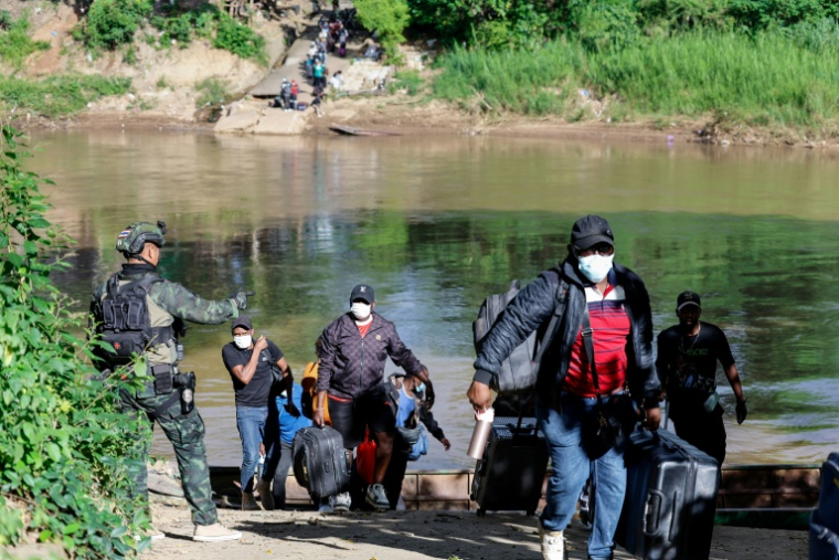 Des personnes de différents pays, qui travaillaient au complexe du parc KK en Birmanie et ont traversé la rivière Moei pour se rendre en Thaïlande, transportent leurs affaires après avoir débarqué d'un bateau dans le district de Mae Sot, dans la province de Tak, le 24 octobre 2025 ( THAI NEWS PIX / Sarot Meksophawannakul )