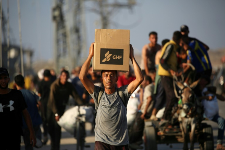 Des Palestiniens marchent le long d'une route de retour d'un point de distribution d'aide de la Fondation humanitaire de Gaza (GHF,) près du camp de réfugiés de Nousseirat, dans le centre de la bande de Gaza, le 25 juin 2025 ( AFP / Eyad BABA )