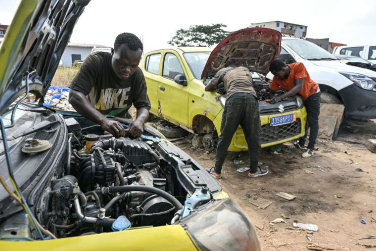 Des mécaniciens informels travaillent sur des moteurs de voiture dans le quartier d'Angré, à Abidjan, la capitale économique ivoirienne, le 21 juillet 2026. ( AFP / Issouf SANOGO )