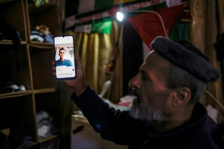 Samir Abou Salah, un Palestinien de Gaza, montre sur son téléphone une photo de son fils, tué à Gaza en janvier 2026, alors qu'il se tient dans sa tente dans un camp installé au stade de football de Naplouse, dans le nord de la Cisjordanie occupée, le 7 mai 2026 ( AFP / Zain JAAFAR )