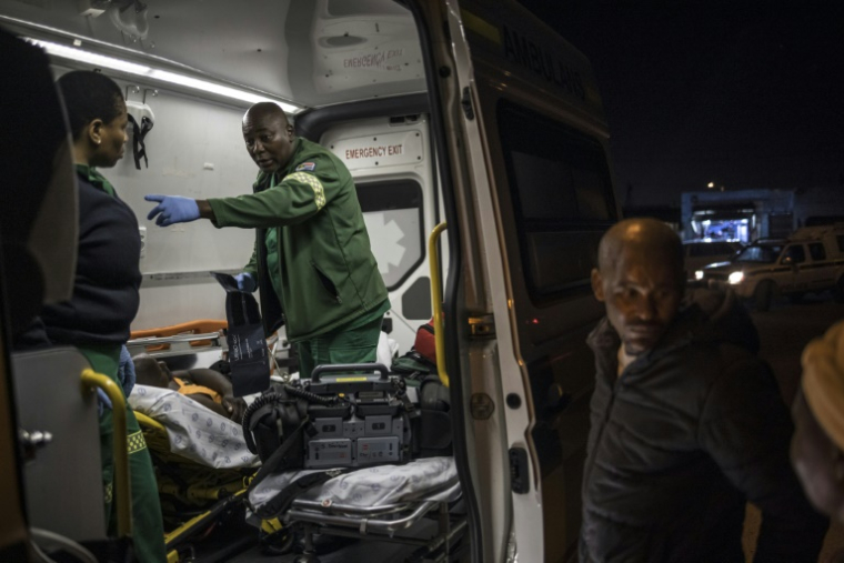 L'ambulancier Mawethu Ntintini (c) et sa collègue Ntombikayisi Jok prennent en charge un blessé lors d'une intervention au township Philippi, près du Cap, le 15 avril 2025 en Afrique du Sud ( AFP / MARCO LONGARI )