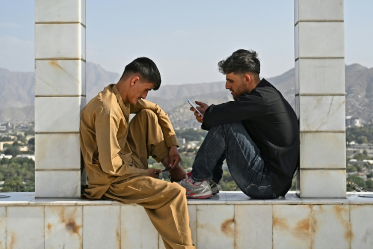 Des jeunes Afghans consultent leurs smartphones, sur la colline de Wazir Akbar Khan, à Kaboul, le 10 août 2026 ( AFP / Wakil KOHSAR )