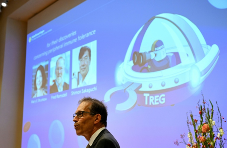 Le secrétaire général du comité Nobel, Thomas Perlmann, devant un écran affichant les portraits (g-d) de Mary E Brunkow, Fred Ramsdell et Shimon Sakaguchi co-lauréats du prix Nobel de médecine, lors d'une conférence de presse sur leurs travaux à l'Institut Karolinska de Stockholm, en Suède, le 6 octobre 2025 ( AFP / Jonathan Nackstrand )
