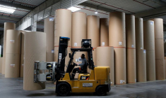 Un employé transporte une bobine de papier géante