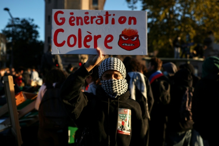 Un homme tient une pancarte pendant la manifestation contre la "vie chère", le 17 octobre 2026 à Paris ( AFP / SIMON WOHLFAHRT )