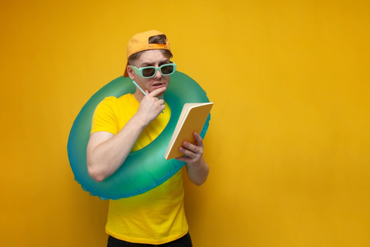 (Crédits photo : Adobe Stock - Jeune homme en tenue décontractée faisant le point sur sa check list de vacances)