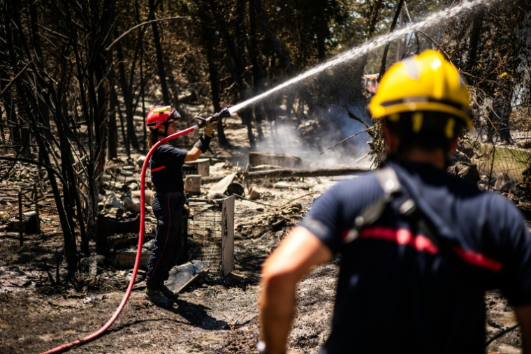Un pompier lutte à la lance pour empêcher le feu de reprendre à Ille-sur-Têt, près de Perpignon, le 6 juillet 2026 dans les Pyrénées-Orientales ( AFP / Jean-Christophe MILHET )