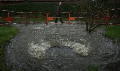 Un habitant passe devant une bouche d'égout débordant d'eaux usées non traitées près de la station de pompage de Taussat à Lanton, dans le bassin d'Arcachon, le 5 février 2026 en Gironde ( AFP / Philippe LOPEZ )