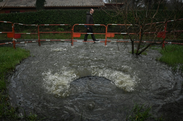 Un habitant passe devant une bouche d'égout débordant d'eaux usées non traitées près de la station de pompage de Taussat à Lanton, dans le bassin d'Arcachon, le 5 février 2026 en Gironde ( AFP / Philippe LOPEZ )