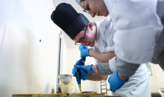 Alexandre Bisson, 21 ans, atteint d'un handicap cognitif dû à un trouble du spectre autistique, prépare des desserts dans la cuisine d'un restaurant d'entreprise où il est apprenti pâtissier. il est aidé par la chef pâtissière Myriam Konforti, à Paris, le 17 février 2023. ( AFP / ANNE-CHRISTINE POUJOULAT )