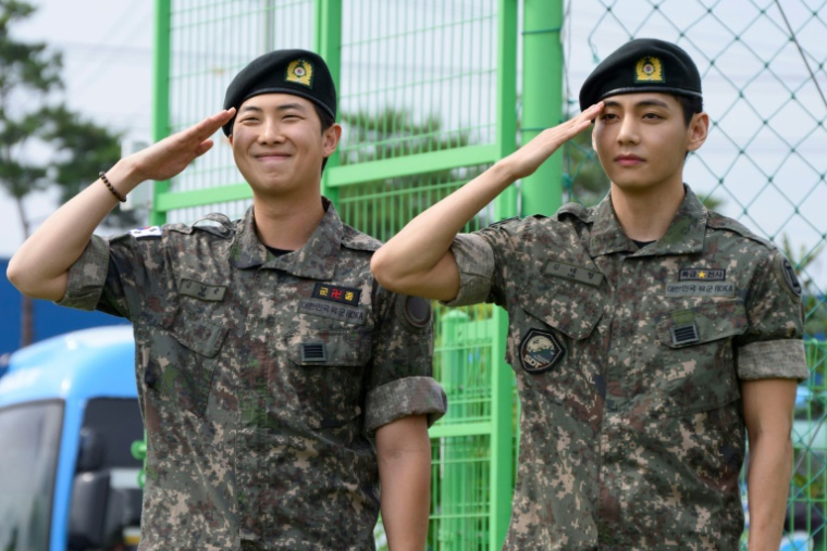 Les membres du boys band K-pop BTS RM (g) et V font un salut militaire dans un centre sportif en plein air à Chuncheon, en Corée du Sud, après avoir été libérés de leur service obligatoire le 10 juin 2025 ( AFP / Shin Yong-ju )