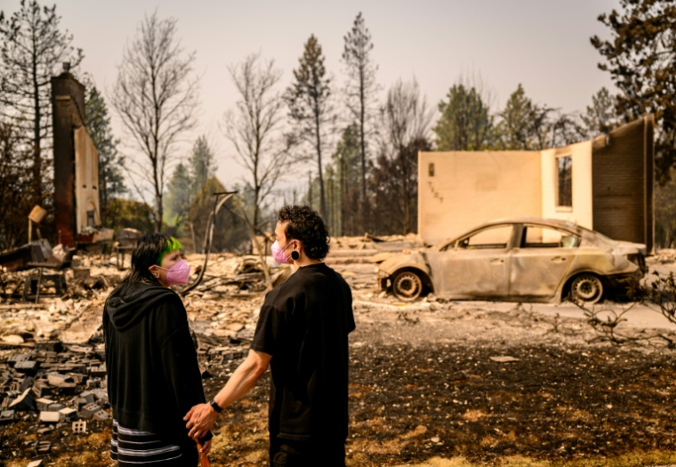 Un couple revient devant sa maison réduite en cendres, à Spokane, dans l'Etat de Washington, le 4 août 2026 ( AFP / Josh Edelson )