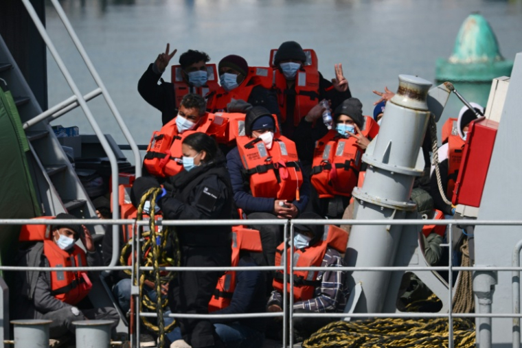 Des migrants s'apprêtent à débarquer d'un bateau des garde-côtes britanniques au port de Douvres (Royaume-Uni) après avoir été secourus lors de leur traversée de la Manche depuis la France, le 15 avril 2022 ( AFP / Daniel LEAL )