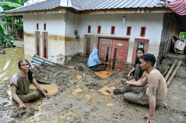 Des habitants dégagent une épaisse couche de boue à l’entrée d’une maison inondée à la suite de crues soudaines à Meureudu, dans la province d’Aceh, en Indonésie, le 28 novembre 2025 ( AFP / CHAIDEER MAHYUDDIN )