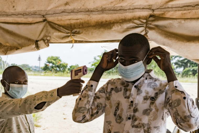 Un agent sanitaire à la frontière du poste de Busunga, entre l'Ouganda et la République démocratique du Congo, prend la température d'un voyageur à l'aide d'un thermomètre infrarouge sans contact à Bundibugyo, le 18 mai 2026.  ( AFP / Badru Katumba )