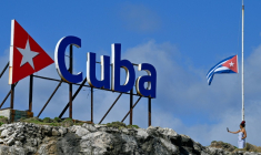 Une touriste prend un selfie alors qu’elle se tient à côté d’un drapeau national cubain en berne à La Havane, le 5 janvier 2026.  ( AFP / Adalberto ROQUE )