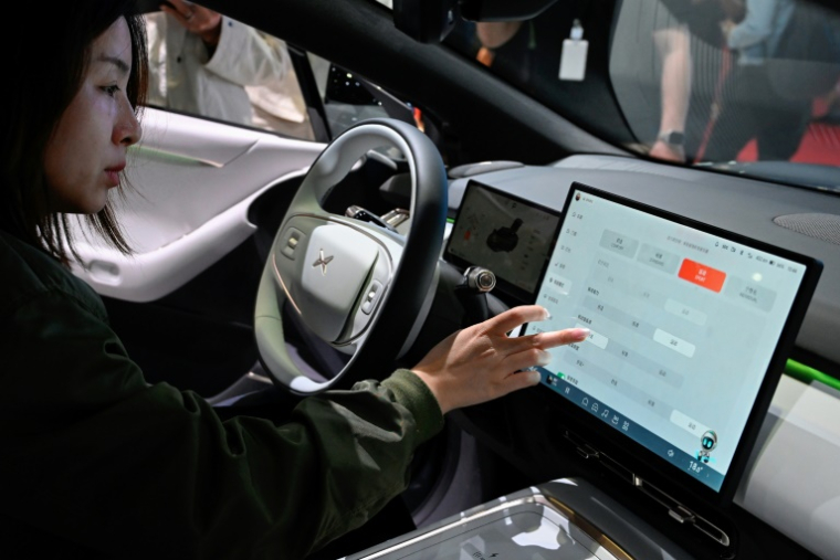 Une visiteuse découvre l'habitacle d'un véhicule P6 de Xpeng lors du salon automobile de Shanghai, le 25 avril 2025 ( AFP / WANG Zhao )