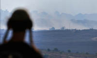 Un homme à un point de vue dans le sud d'Israël, surplombant la bande de Gaza, regarde la fumée s'élever pendant les frappes israéliennes sur la capitale assiégée le 15 juillet 2025 ( AFP / Jack GUEZ )