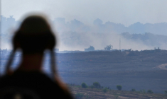 Un homme à un point de vue dans le sud d'Israël, surplombant la bande de Gaza, regarde la fumée s'élever pendant les frappes israéliennes sur la capitale assiégée le 15 juillet 2025 ( AFP / Jack GUEZ )