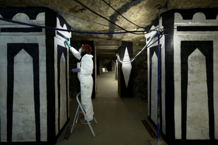 Un restaurateur d'art travaille sur un tableau pendant des travaux de restauration des Catacombes de Paris, le 24 mras 2026 ( AFP / Kenzo TRIBOUILLARD )