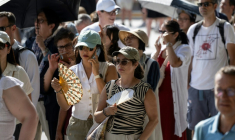 Des touristes avec des éventails devant la cathédrale Notre-Dame, le 16 août 2025 à Paris ( AFP / Martin LELIEVRE )