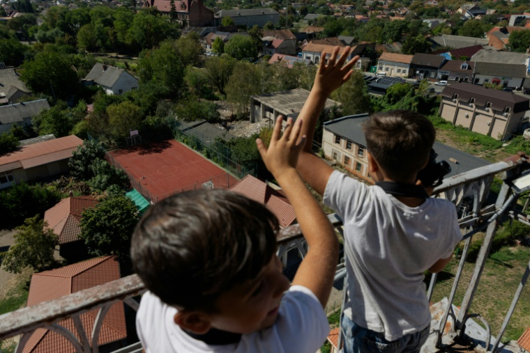 Des enfants admirent la vue sur leur ville depuis la terrasse d'observation de l'église de l'Exaltation de la Sainte-Croix à Berehove, dans la région de Transcarpatie, à l'ouest de l'Ukraine, le 28 août 2026 ( AFP / Tetiana DZHAFAROVA )