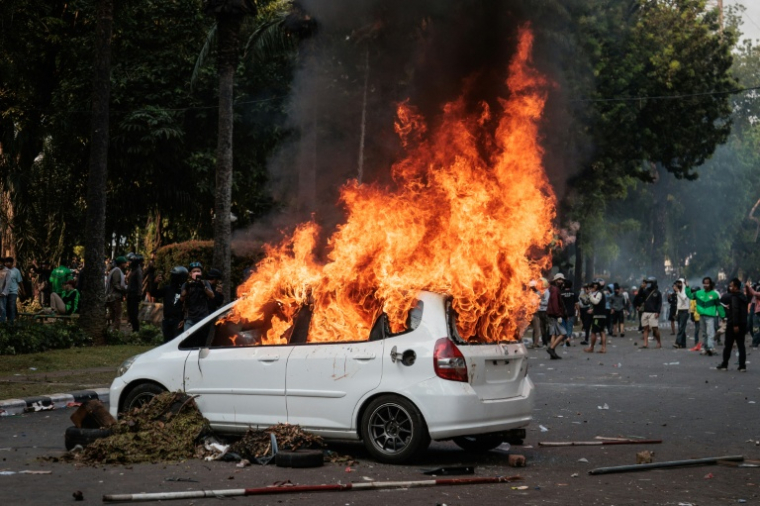 Une voiture brûle après avoir été incendiée lors d'une manifestation contre la Brimob, une unité de police, le 29 août 2025 à Jakarta ( AFP / Aditya Aji )