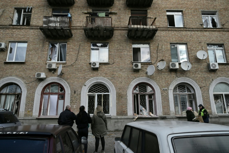 Des habitants regardent un immeuble résidentiel endommagé par des frappes aériennes russe à Kiev, le 22 octobre 2025 en Ukraine ( AFP / Genya SAVILOV )