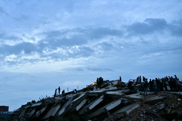 Des secouristes et des bénévoles travaillent dans les ruines d'un immeuble effondré après le double séisme au Venezuela, le 3 juillet 2026 à Caraballeda, dans l’État de La Guaira  ( AFP / MARTIN BERNETTI )