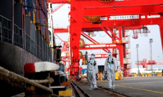 Des agents de la police des frontières en combinaison de protection patrouillent à côté d'un porte-conteneurs dans le port de Nanjing