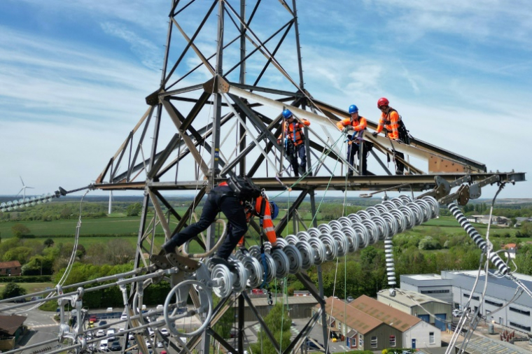 Des apprentis suivent une formation sur un pylône au centre de formation de National Grid à Eakring, dans le centre de l'Angleterre, le 28 avril 2025, perchés à 45 mètres de hauteur ( AFP / Darren Staples )