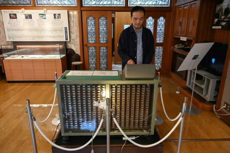 Un guide fait une démonstration sur une calculatrice Casio 14-A, le 25 novembre 2025 au musée Toshio Kashio à Tokyo ( AFP / GREG BAKER )