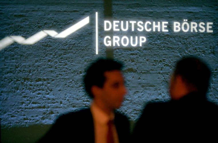 Des invités se tiennent devant un panneau indiquant le groupe Deutsche Boerse, propriétaire de la bourse allemande