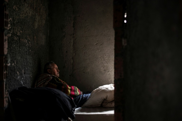 Antonio Lemos, un aide-cuisinier à la retraite, se repose sur un matelas posé au sol dans une maison abandonnée où il vit, dans le quartier de Belem à Lisbonne, le 17 avril 2025 au Portugal ( AFP / PATRICIA DE MELO MOREIRA )