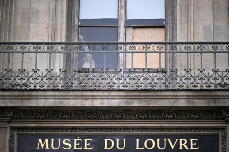 Une personne derrière la fenêtre par laquelle sont entrés les voleurs au musée du Louvre la veille, à Paris, le 20 octobre 2025 ( AFP / JULIEN DE ROSA )