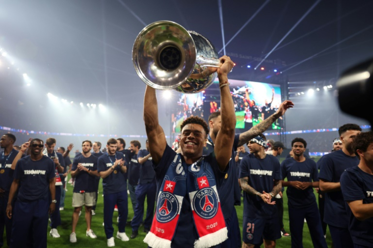 Le milieu de terrain du PSG Désiré Doué brandit le trophée de la Ligue des champions, le 1er juin 2025, lors des festivités au Parc des Princes ( POOL / Franck FIFE )