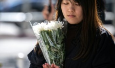 Une femme se recueille avant de déposer des fleurs devant le complexe résidentiel de Wang Fuk Court ravagé par un incendie, le 29 novembre 2025 à Hong Kong ( AFP / Philip FONG )