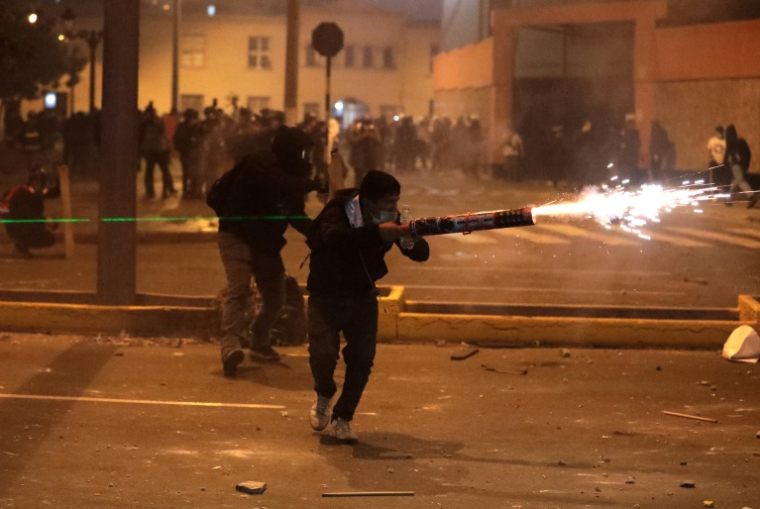 Un manifestant utilise des feux d'artifice contre les policiers anti-émeutes lors d'affrontements qui ont suivi une manifestation contre le président par intérim du Pérou, José Jeri, à Lima, le 15 octobre 2025 ( AFP / CONNIE FRANCE )