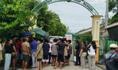 Des élèves et leurs parents attendent l'autorisation de pénétrer dans l'enceinte du lycée San José, à Tacloban, au lendemain d'une fusillade, le 23 juin 2026 aux Philippines  ( AFP / Noel  Sianosa )