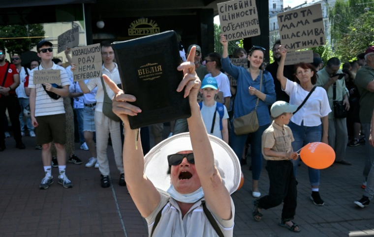 Une dame brandit une bible durant une contre-manifestation s'opposant à la Marche des Fiertés, à Kiev, Ukraine, le 21 juin 2026 ( AFP / Sergei SUPINSKY )
