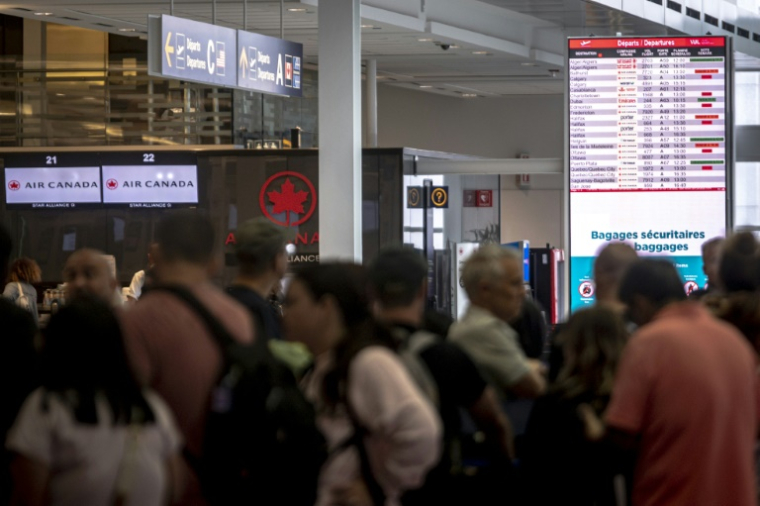 Des voyageurs consultent un panneau d'information sur les vols annulés d'Air Canada à l'aéroport Pierre-Elliott Trudeau à Montréal, au Québec, le 17 août 2025 au Canada ( AFP / ANDREJ IVANOV )