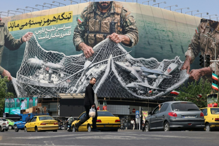 Des véhicules passent devant un panneau d'affichage géant portant l'inscription: "Le détroit d'Ormuz reste fermé"  sur la place de la Révolution à Téhéran, le 28 avril 2026 ( AFP / ATTA KENARE )