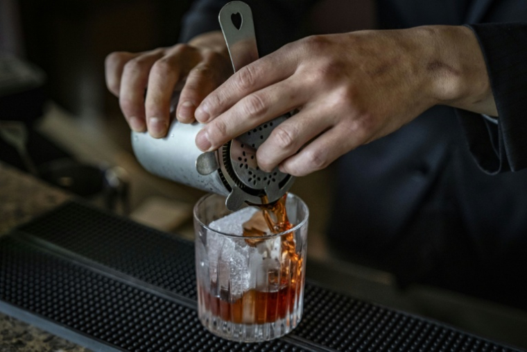 Le barman Shingo Miyachi prépre un cocktail negroni avec un glaçon de l'usine kuramoto Ice au bar de l'hôtel Hilton de Narita, au Japon, le 19 juin 2026 ( AFP / Yuichi YAMAZAKI )